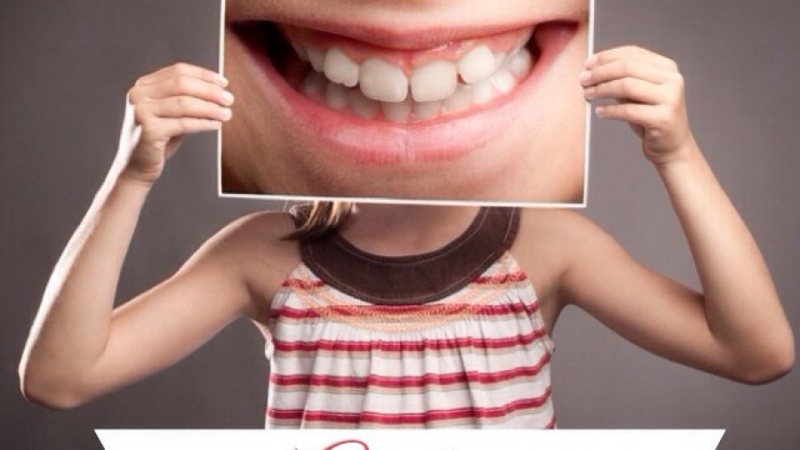 Picture of a girl holding a photo of teeth for National Oral Health Month post